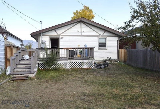 rear view of house featuring a yard and a wooden deck