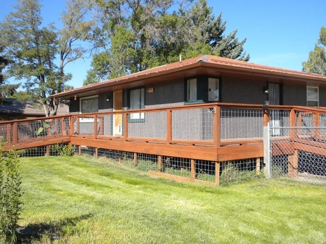 back of property with a wooden deck and a lawn