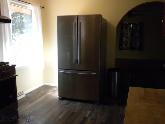 kitchen with black gas stove, stainless steel fridge, and dark wood-type flooring