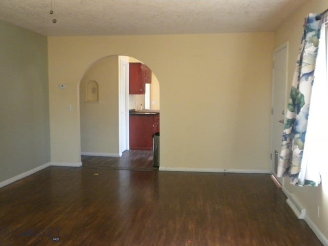 unfurnished room featuring a textured ceiling and dark hardwood / wood-style flooring