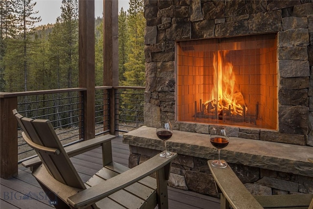 2250 Outlook Trl, Big Sky, MT 59716 - wooden deck with a lit fireplace and a wooded view