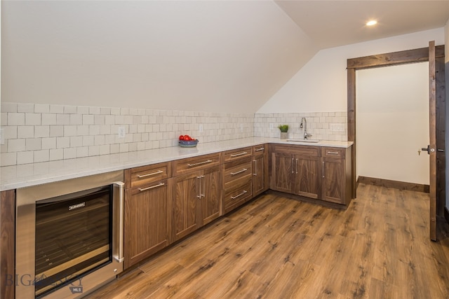 kitchen featuring sink, tasteful backsplash, hardwood / wood-style floors, beverage cooler, and lofted ceiling