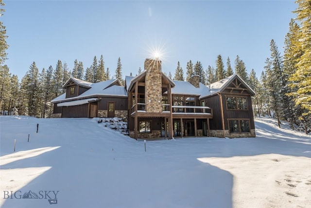 2250 Outlook Trl, Big Sky, MT 59716 - snow covered house featuring stone siding, a chimney, and a deck