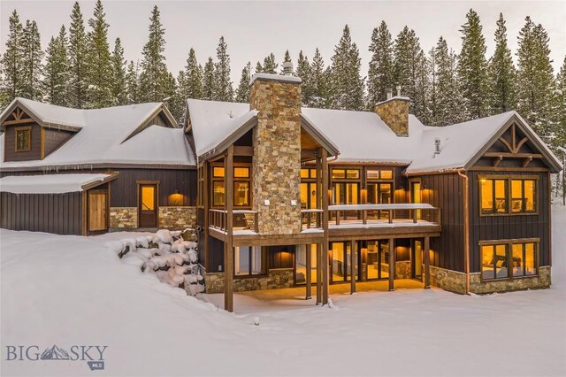 2250 Outlook Trl, Big Sky, MT 59716 - snow covered rear of property with stone siding, a chimney, and board and batten siding