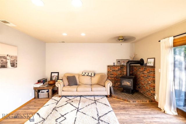 living room featuring a wood stove, ceiling fan, and hardwood / wood-style flooring