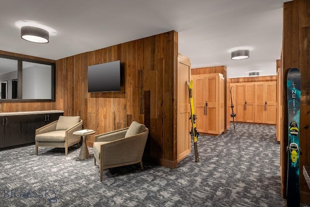 living area with wood walls and dark carpet