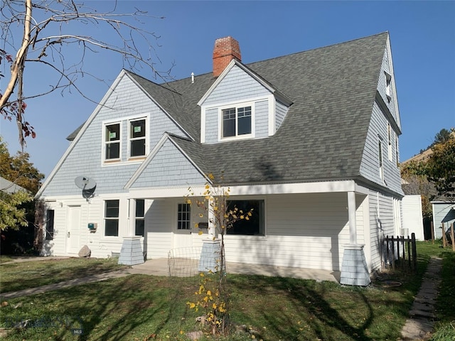 rear view of property featuring covered porch and a lawn