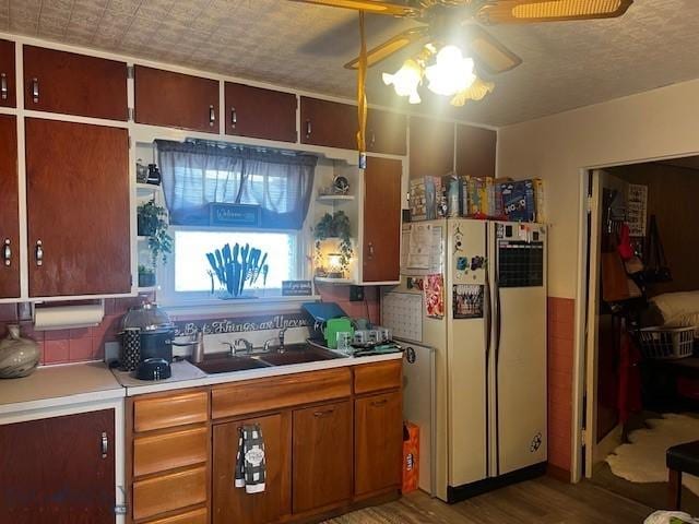 kitchen with wood finished floors, a sink, ceiling fan, light countertops, and freestanding refrigerator