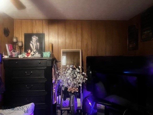 bedroom featuring ceiling fan and wood walls