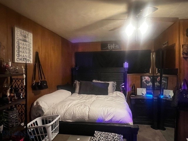 bedroom with ceiling fan and wood walls