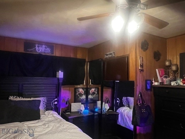 bedroom featuring ceiling fan and wooden walls