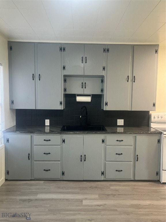 kitchen featuring white electric range oven, sink, and light wood-type flooring