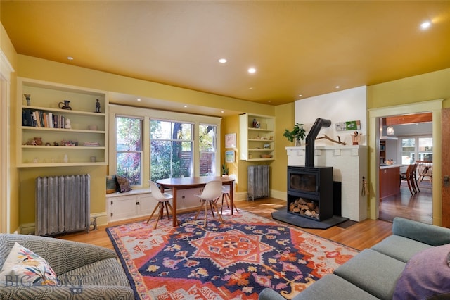 living room with a wood stove, radiator heating unit, and light hardwood / wood-style floors