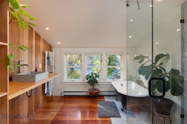 interior space featuring hardwood / wood-style flooring, sink, vaulted ceiling, a baseboard radiator, and wood walls