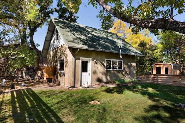 back of property featuring a lawn and a storage unit