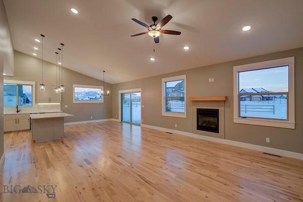 unfurnished living room featuring vaulted ceiling, plenty of natural light, ceiling fan, and light hardwood / wood-style flooring