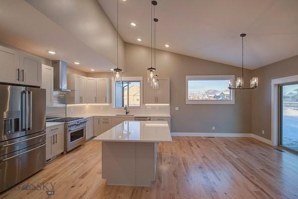 kitchen featuring pendant lighting, wall chimney range hood, a center island, and appliances with stainless steel finishes