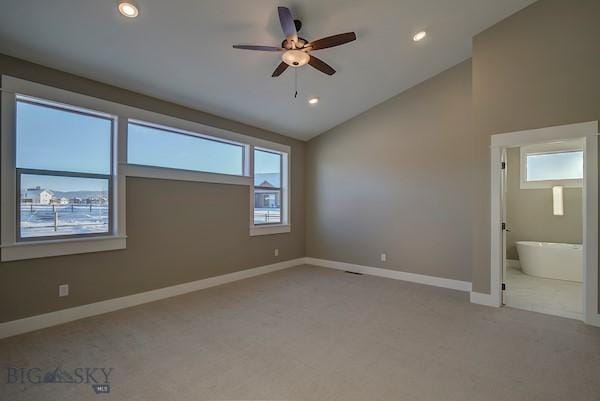 unfurnished bedroom with lofted ceiling, light colored carpet, connected bathroom, and ceiling fan