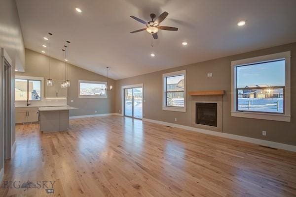 unfurnished living room with high vaulted ceiling, sink, ceiling fan, and light hardwood / wood-style flooring