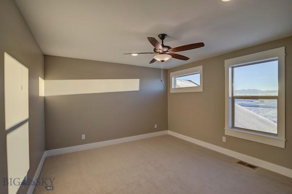 carpeted spare room featuring a water view and ceiling fan