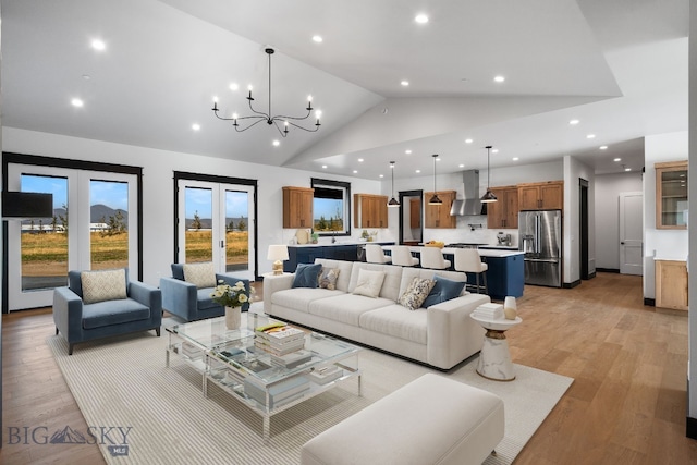 living room with lofted ceiling, an inviting chandelier, french doors, and light hardwood / wood-style floors