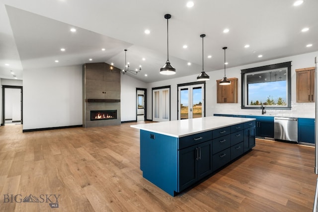 kitchen with lofted ceiling, a center island, stainless steel dishwasher, light hardwood / wood-style floors, and pendant lighting