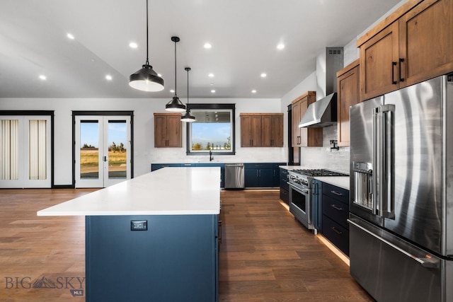 kitchen featuring wall chimney exhaust hood, pendant lighting, high quality appliances, dark hardwood / wood-style floors, and a center island