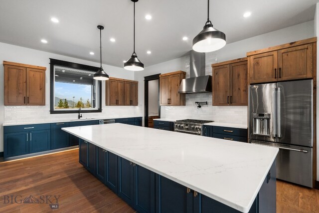 kitchen with dark hardwood / wood-style floors, wall chimney exhaust hood, hanging light fixtures, a spacious island, and appliances with stainless steel finishes