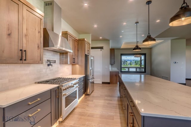 119 Clancy Way, Bozeman, MT 59718 - kitchen featuring premium appliances, wall chimney range hood, a large island, light wood-style floors, and tasteful backsplash