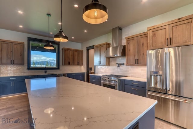 119 Clancy Way, Bozeman, MT 59718 - kitchen featuring high end fridge, wall chimney range hood, light stone countertops, decorative backsplash, and a sink