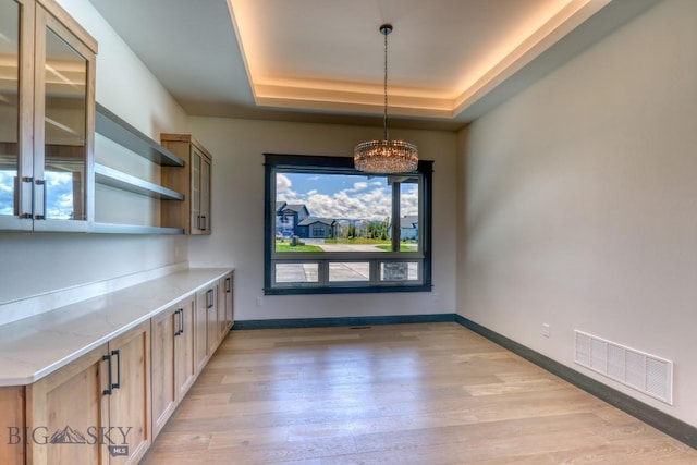 119 Clancy Way, Bozeman, MT 59718 - unfurnished dining area featuring light wood-style floors, a chandelier, baseboards, and a raised ceiling