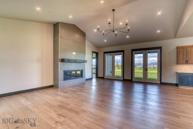 119 Clancy Way, Bozeman, MT 59718 - unfurnished living room featuring a chandelier, light wood-style flooring, a tiled fireplace, baseboards, and high vaulted ceiling