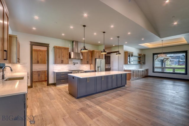 119 Clancy Way, Bozeman, MT 59718 - kitchen featuring wall chimney range hood, stainless steel appliances, a sink, decorative backsplash, and a spacious island