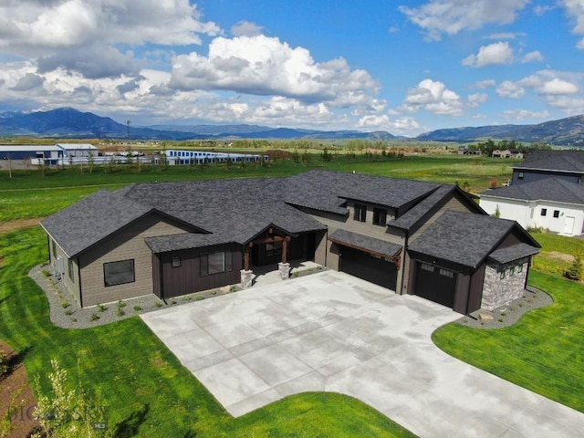 119 Clancy Way, Bozeman, MT 59718 - view of front facade featuring a mountain view, concrete driveway, stone siding, and a front lawn