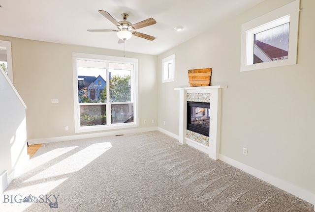 unfurnished living room featuring a multi sided fireplace, carpet, and ceiling fan