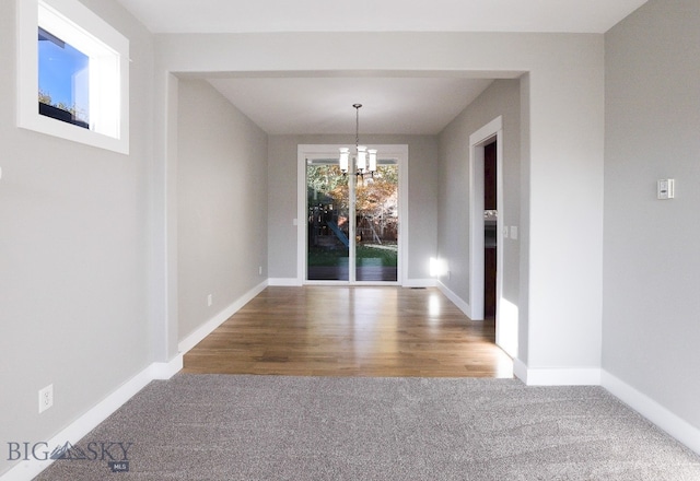 unfurnished dining area with hardwood / wood-style floors and a chandelier