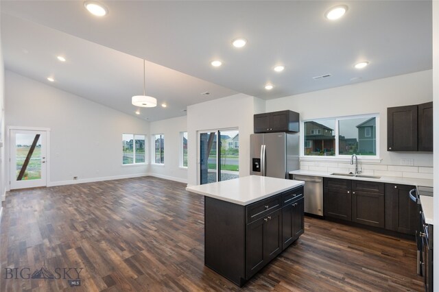 kitchen with appliances with stainless steel finishes, a kitchen island, sink, and dark hardwood / wood-style floors