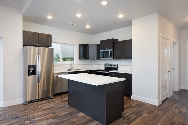 kitchen with sink, appliances with stainless steel finishes, dark wood-type flooring, and a center island