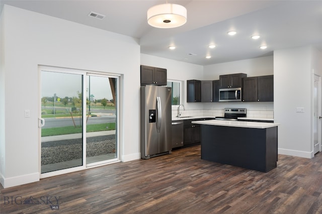 kitchen featuring sink, dark brown cabinets, stainless steel appliances, dark hardwood / wood-style floors, and a center island