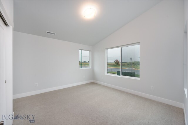 carpeted spare room featuring vaulted ceiling