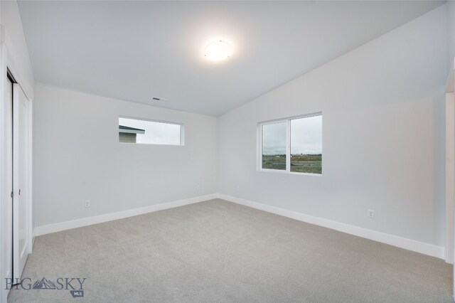 unfurnished room with light colored carpet and vaulted ceiling