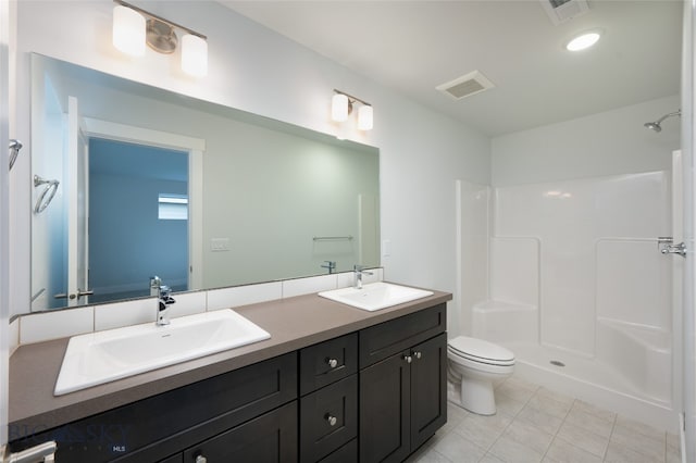 bathroom with tile patterned floors, vanity, walk in shower, and toilet