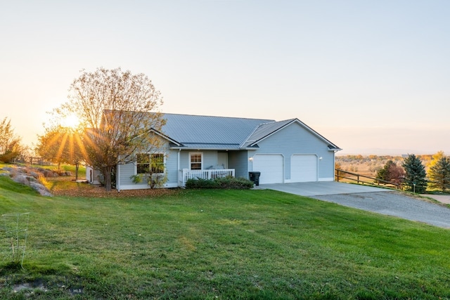 ranch-style home featuring a yard, a garage, and covered porch