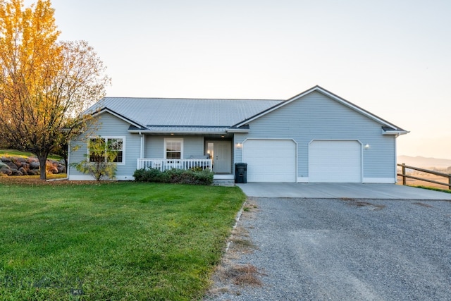 ranch-style home featuring a yard, covered porch, and a garage