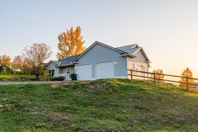 property exterior at dusk featuring a garage and a lawn