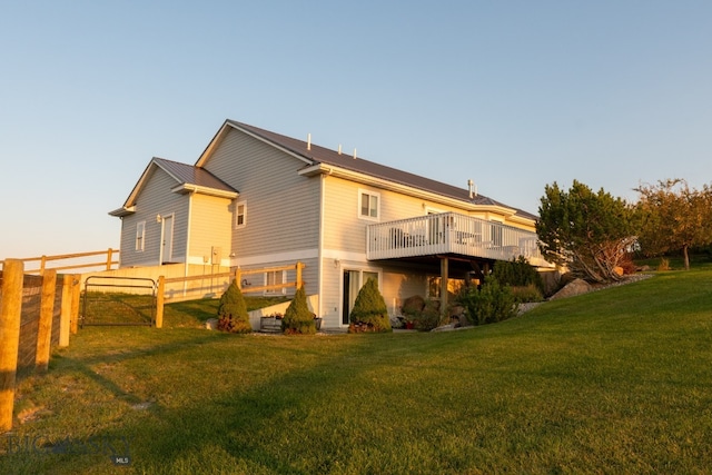 rear view of house featuring a wooden deck and a lawn