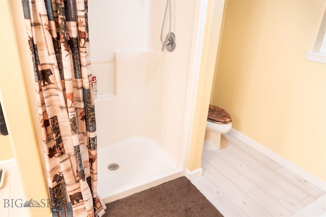 bathroom featuring toilet, hardwood / wood-style flooring, and curtained shower