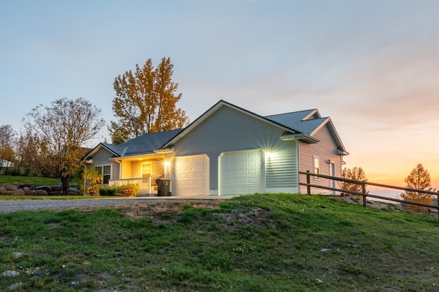 property exterior at dusk with a lawn and a garage