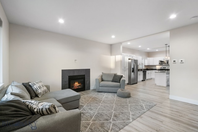 living room featuring light hardwood / wood-style flooring and a tiled fireplace