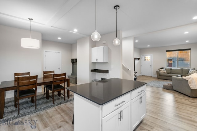 kitchen with light hardwood / wood-style flooring, white cabinetry, decorative light fixtures, and a kitchen island